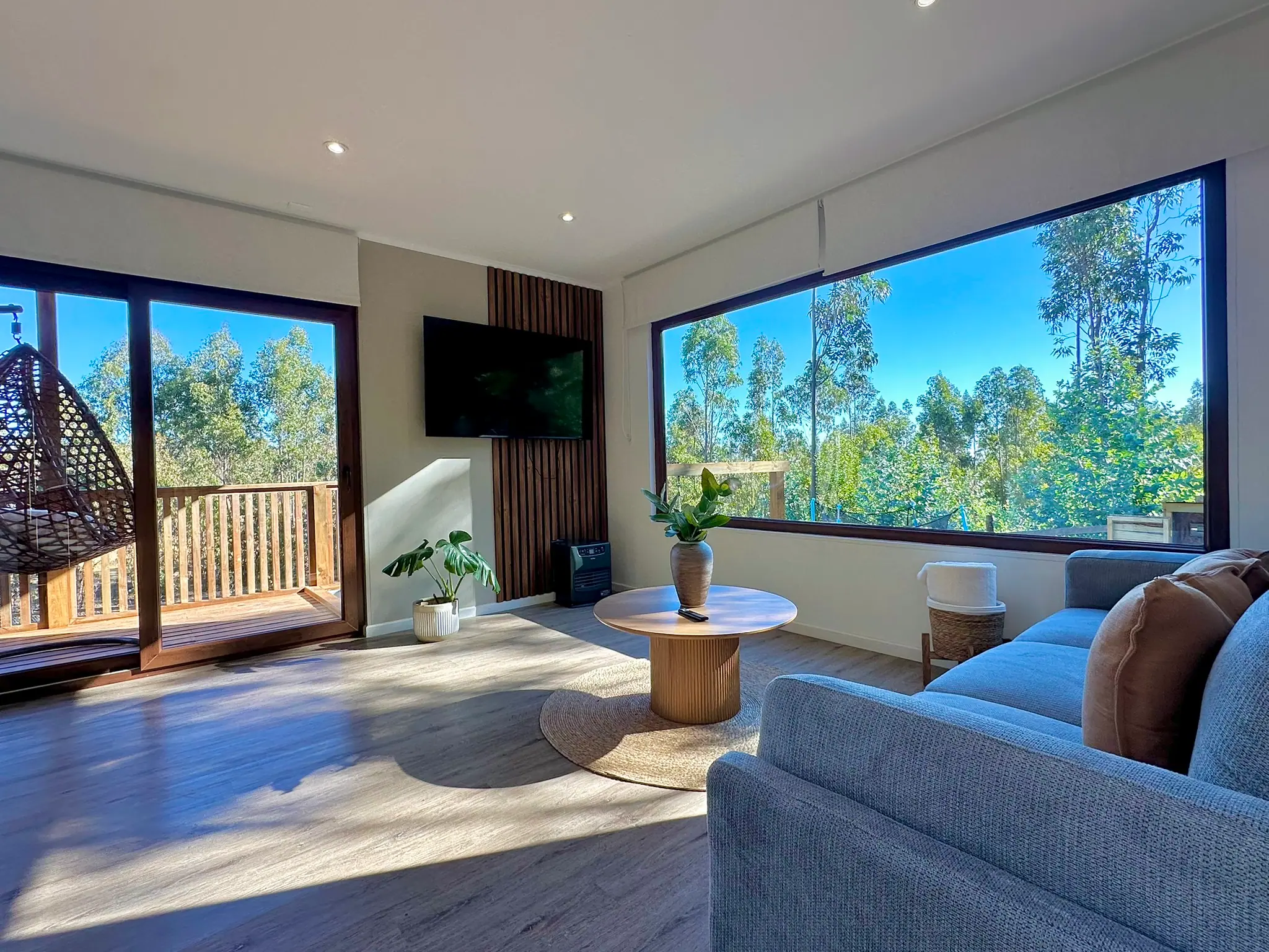 Living de la cabaña Ágata con ventanal al bosque y terraza con silla colgante